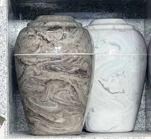 Two marble urns side by side inside a granite niche